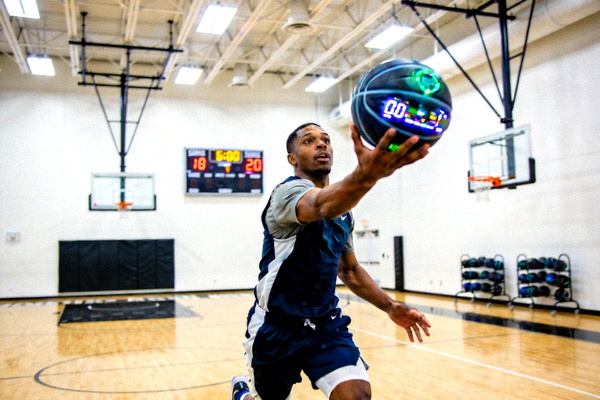 专业篮球运动员在训练馆使用智能篮球进行投篮训练的场景